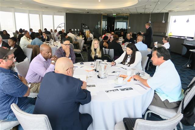 Seven guest appearing to be in conversation while sitting at a large round table at a Edge4Vets event.